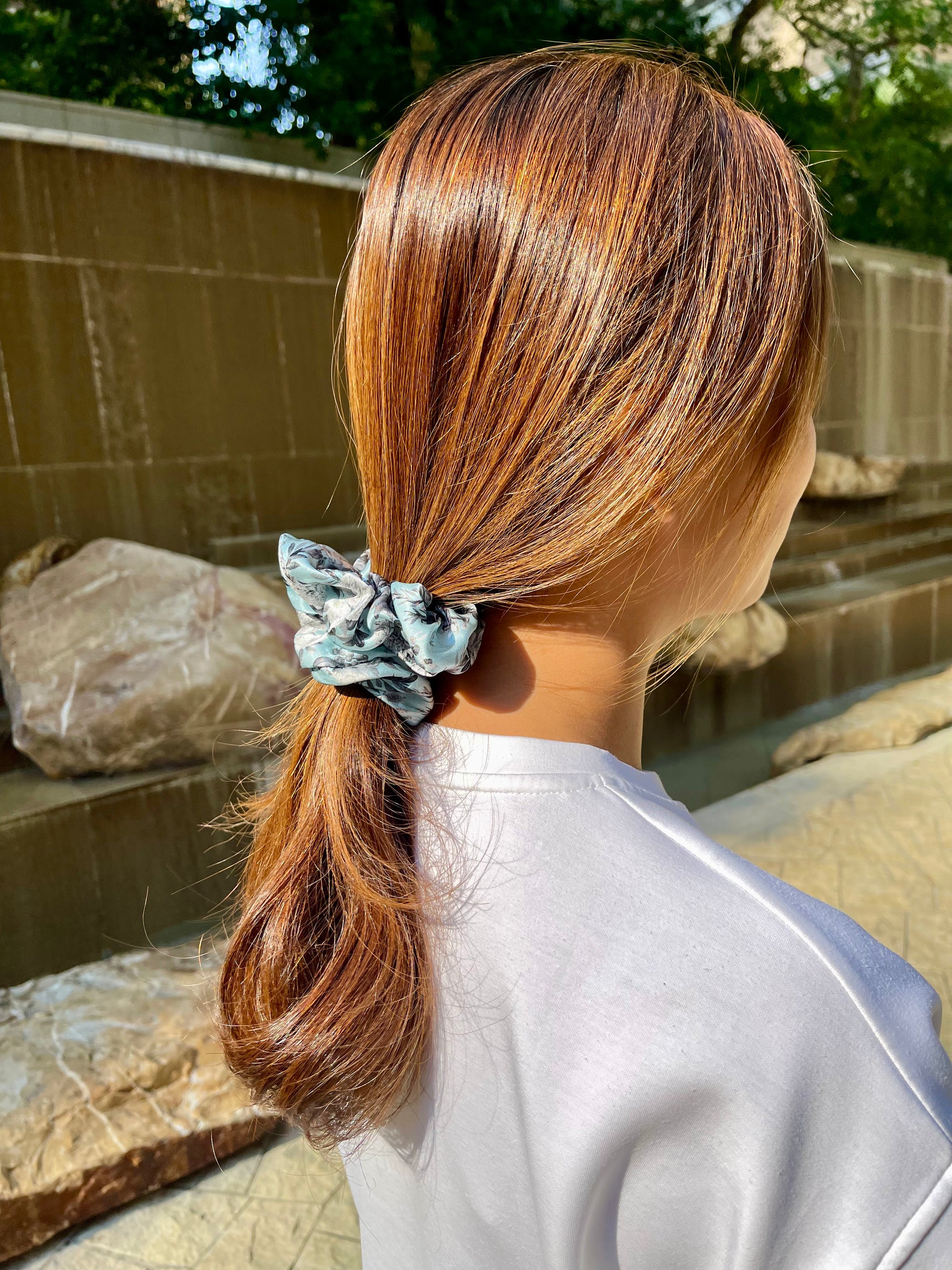 Woman wearing a grey silk scrunchie with grey floral patterns