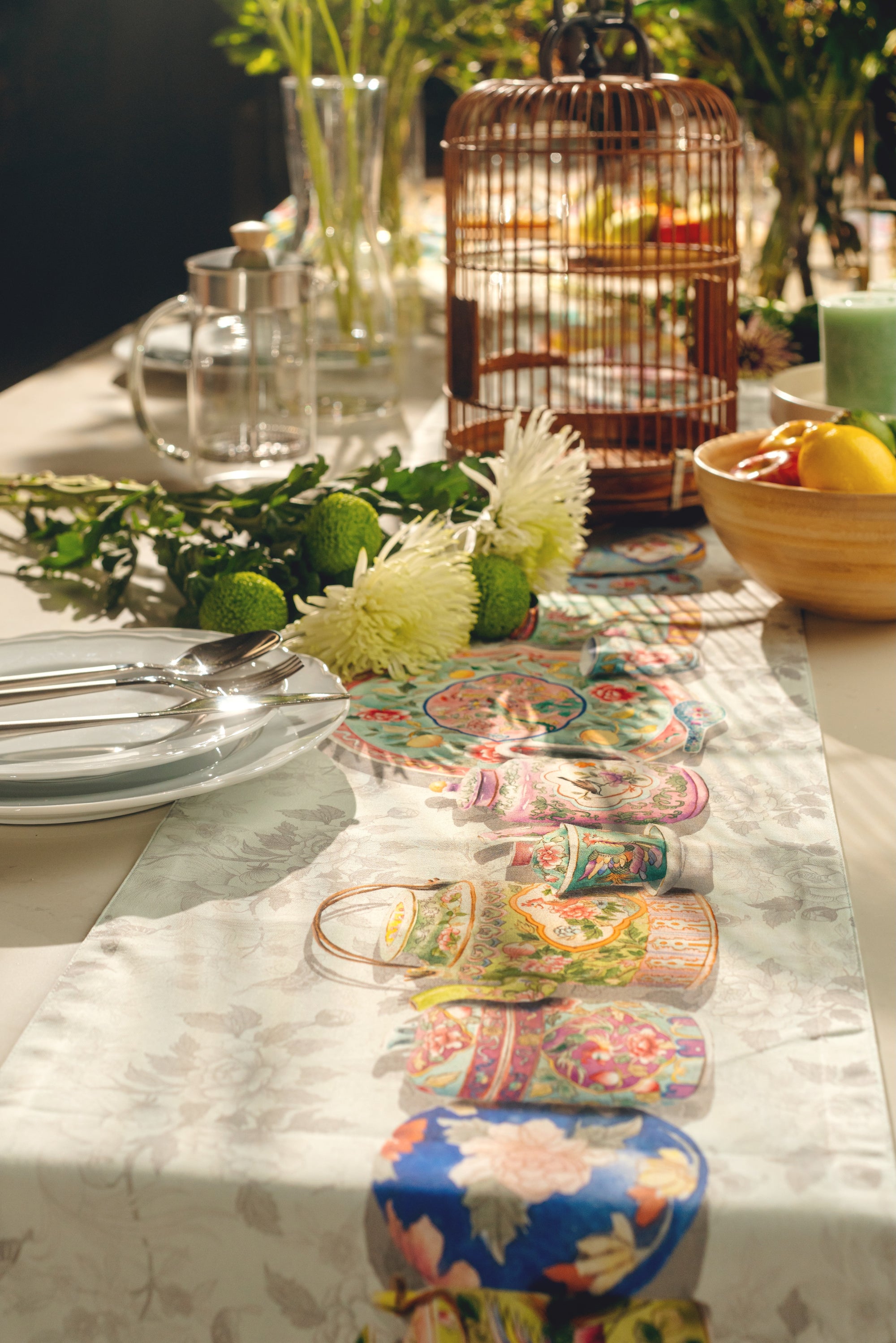 Decorative table setting with colorful plates, flowers, and a birdcage.