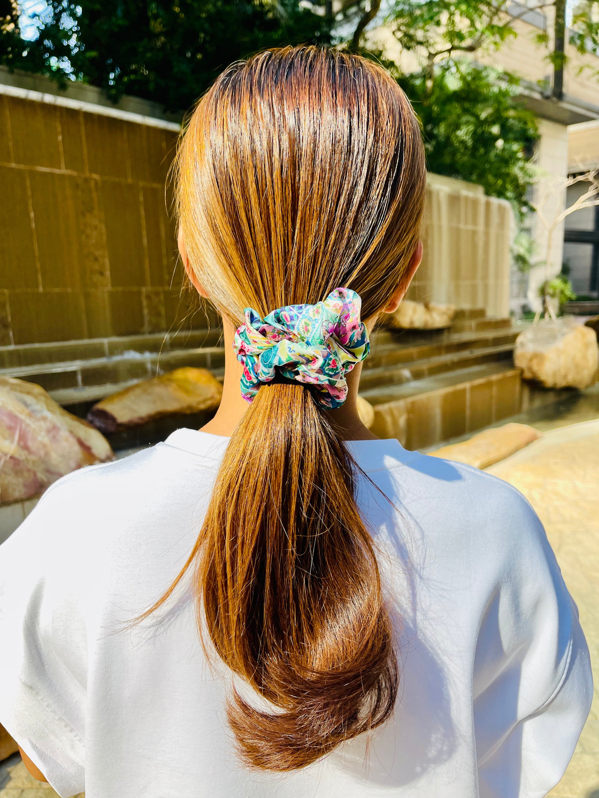 Woman wearing a multicoloured silk scrunchie with tiles and floral design
