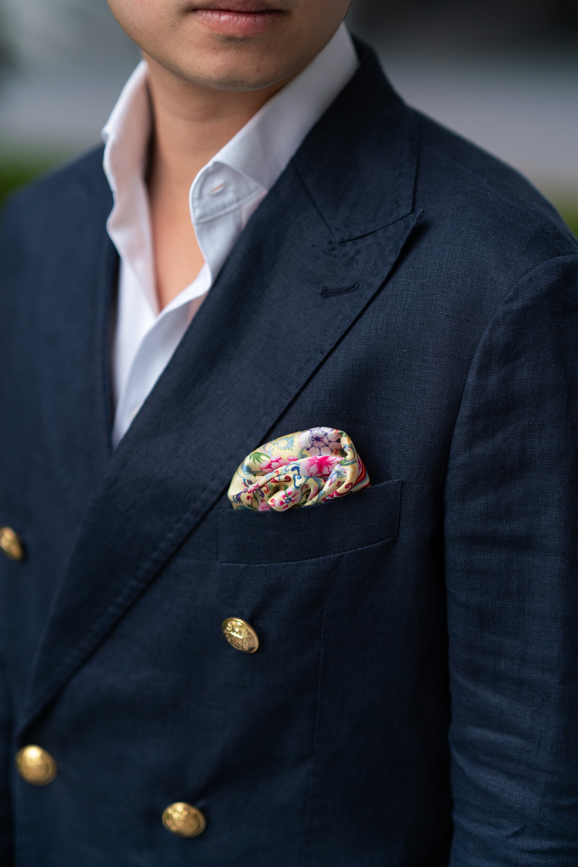 Man wearing a navy suit with a yellow floral pocket square.