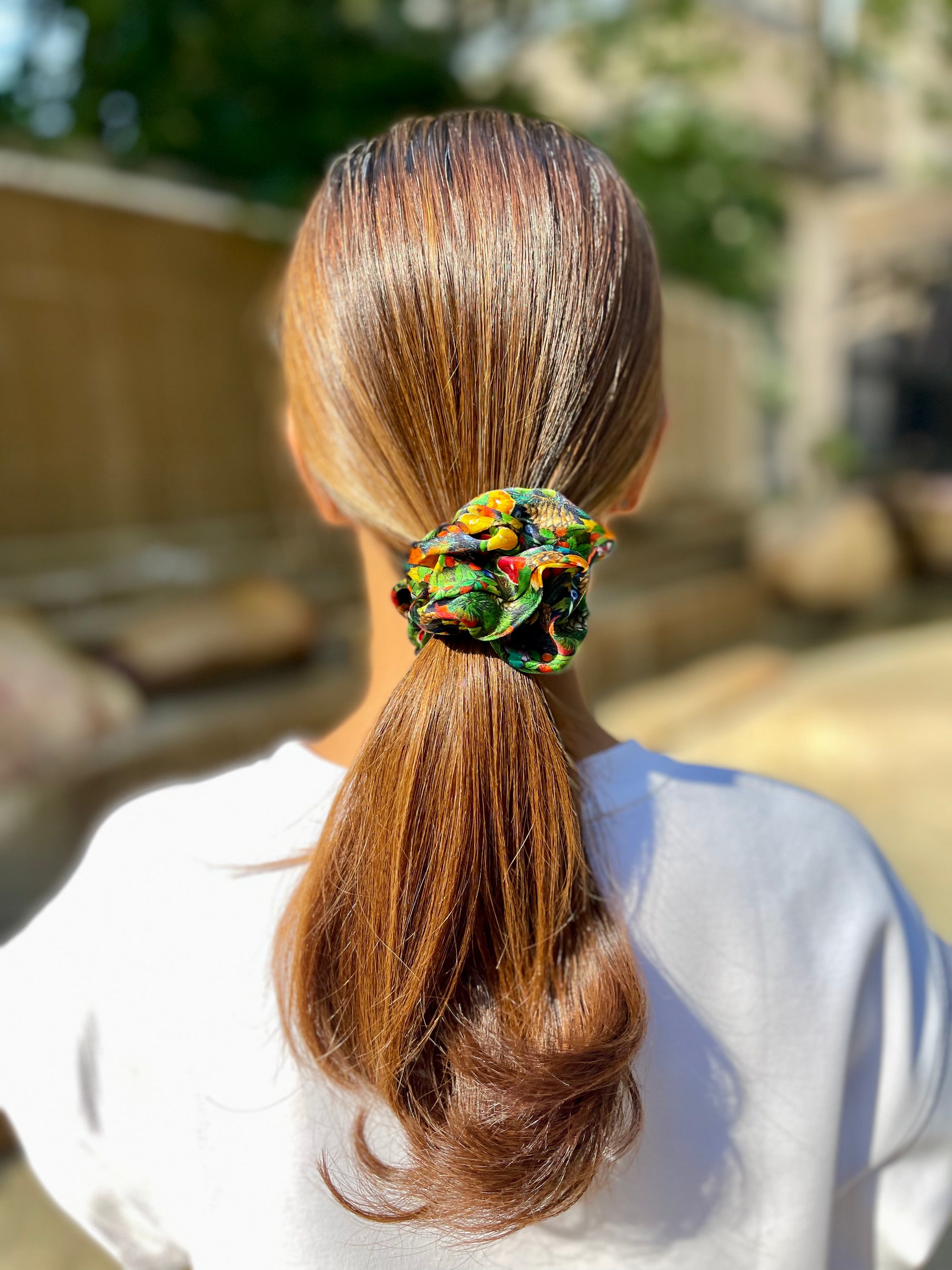 Woman wearing a green silk scrunchie with singapore and christmas themed ornaments
