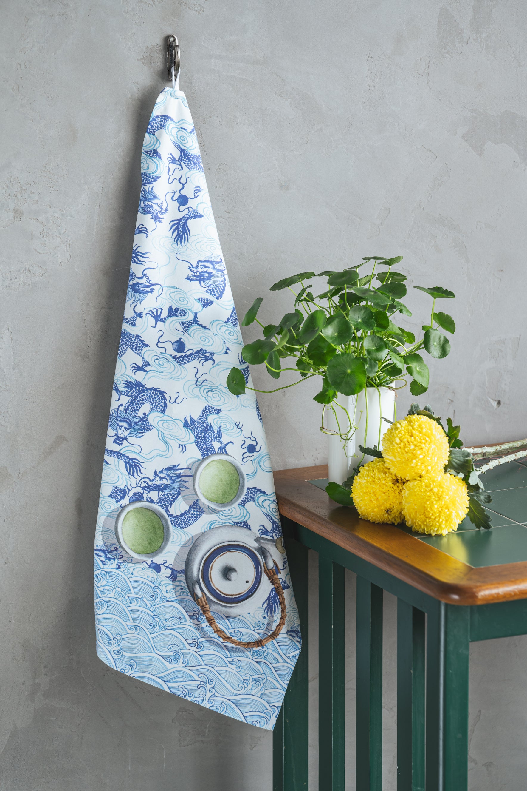 Lifestyle of white dragon tea towel alongside potted plants and flowers