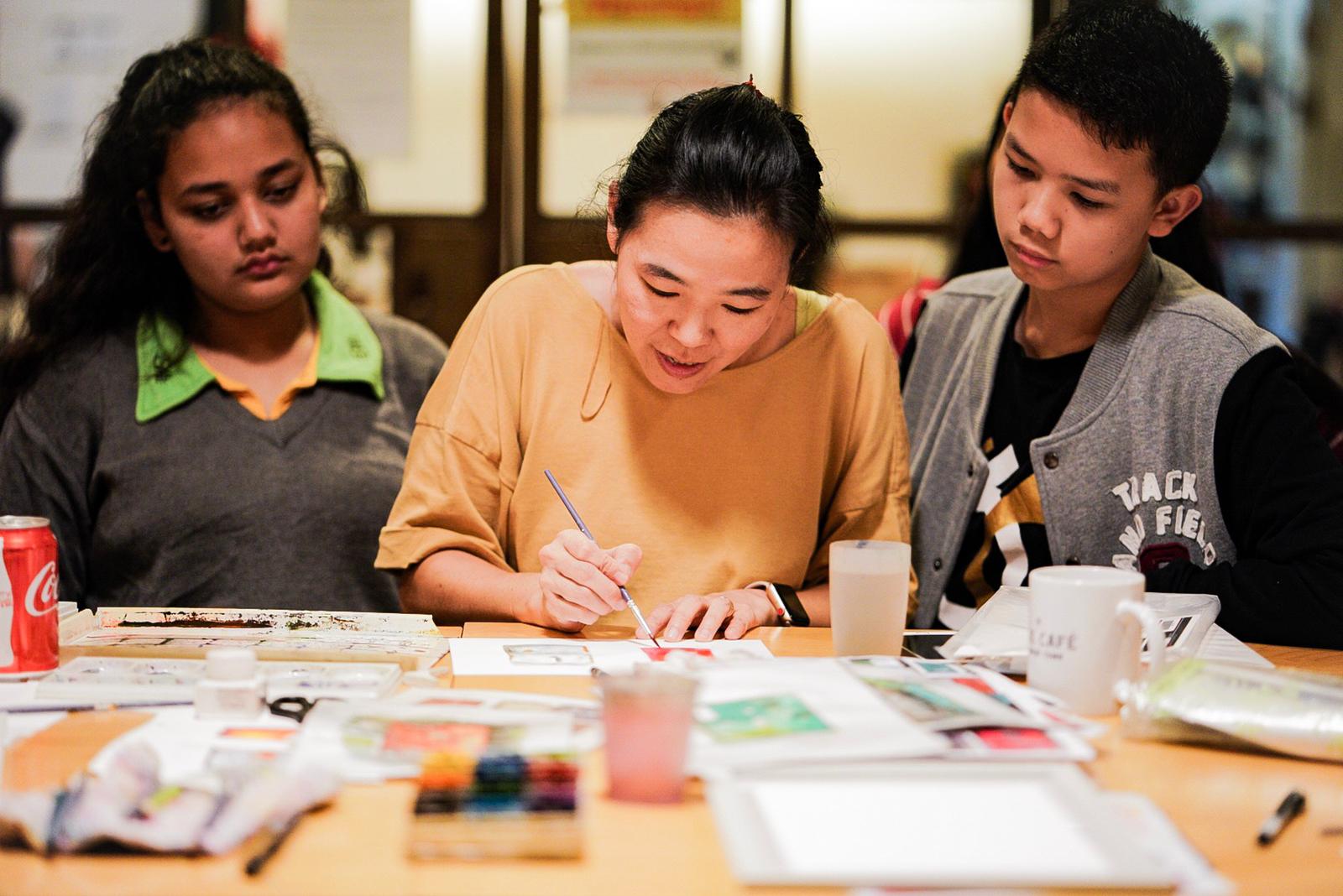 Singlapa instructor teaching watercolor art to students in a creative workshop session