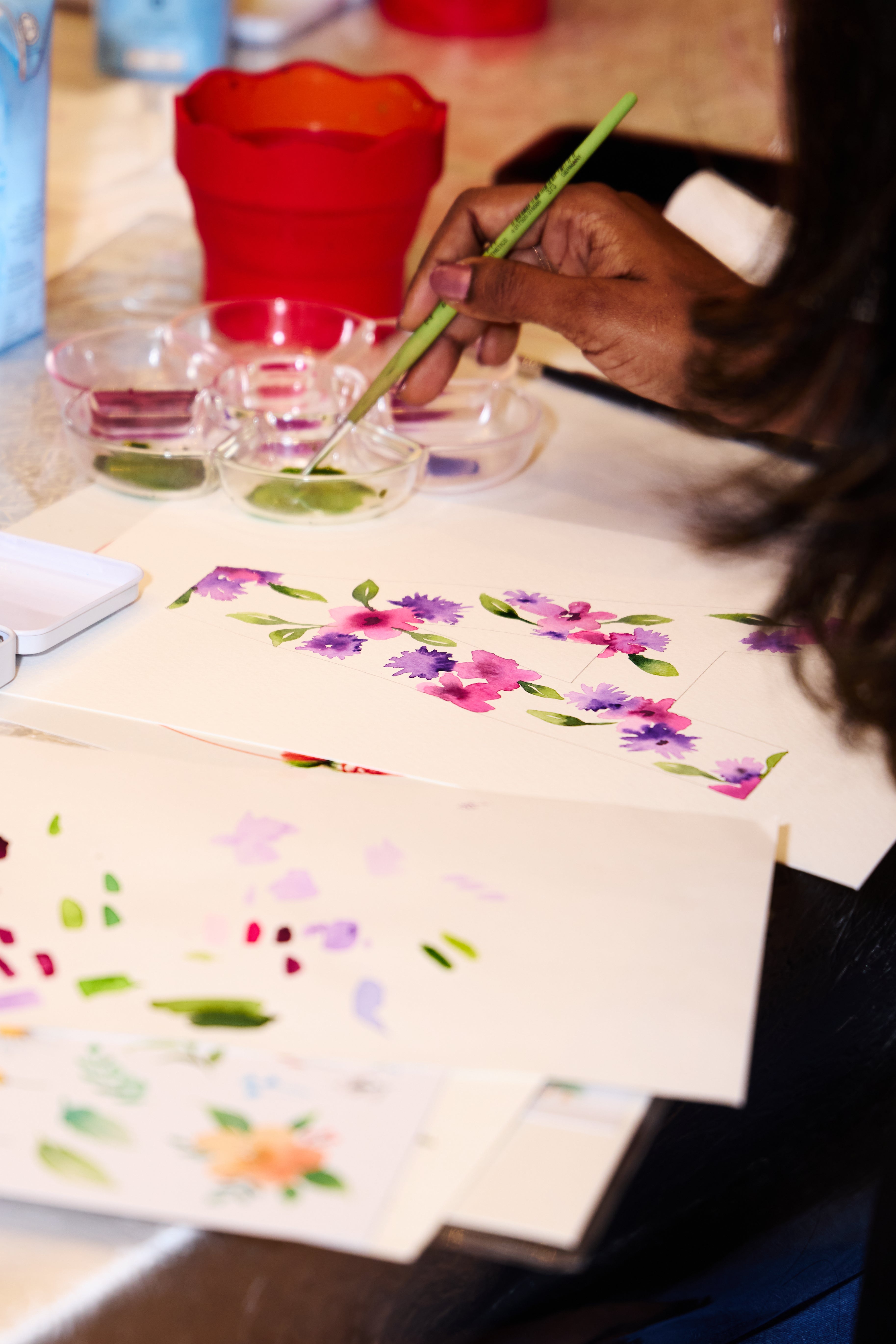 Person painting flowers on a canvas with a brush
