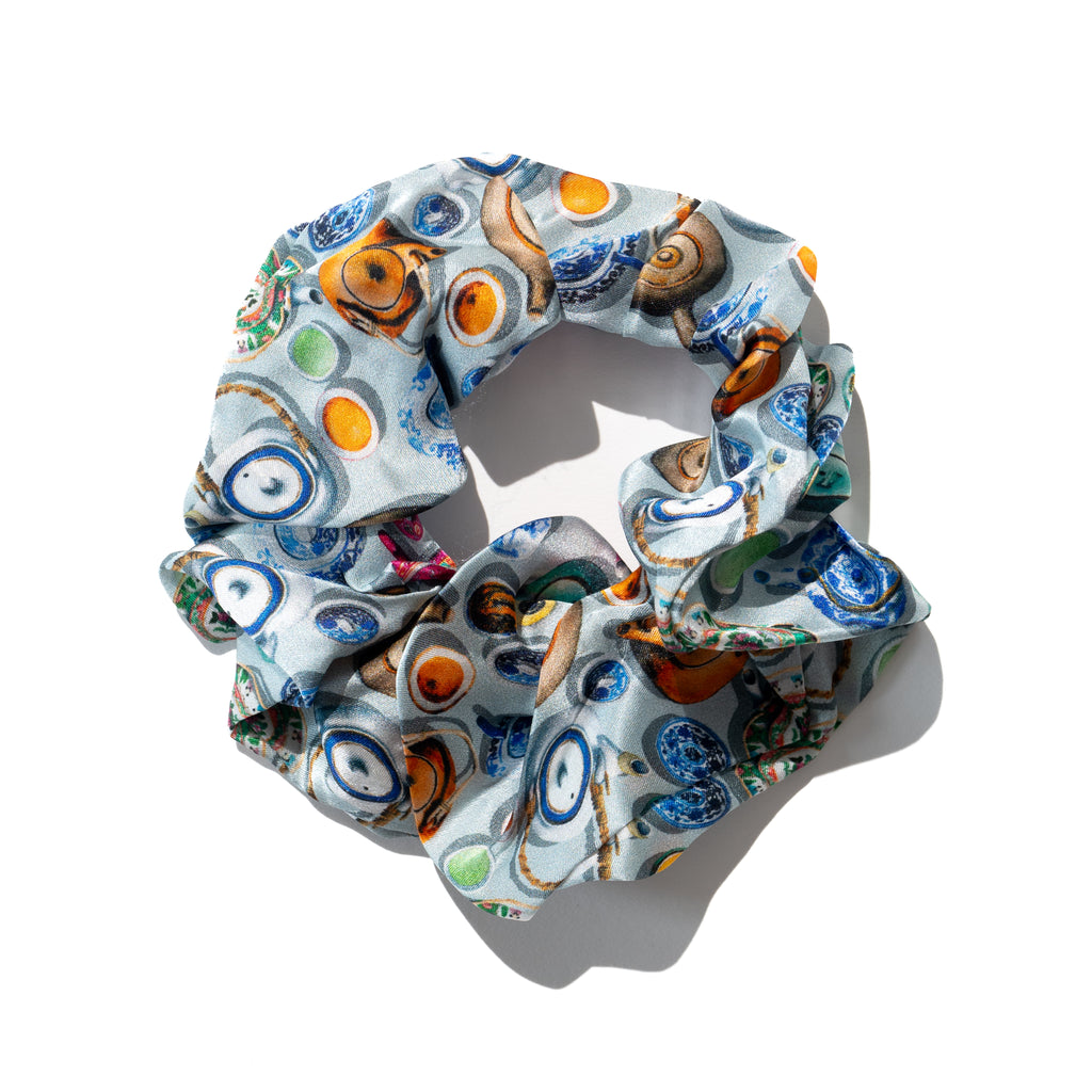 A multicolored silk scrunchie with a pattern of chinese teapots and cups displayed on a light background.