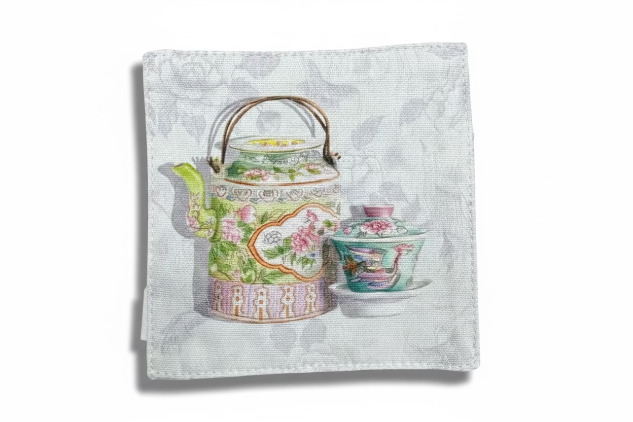 Decorative teapot and teacup set on a patterned fabric background