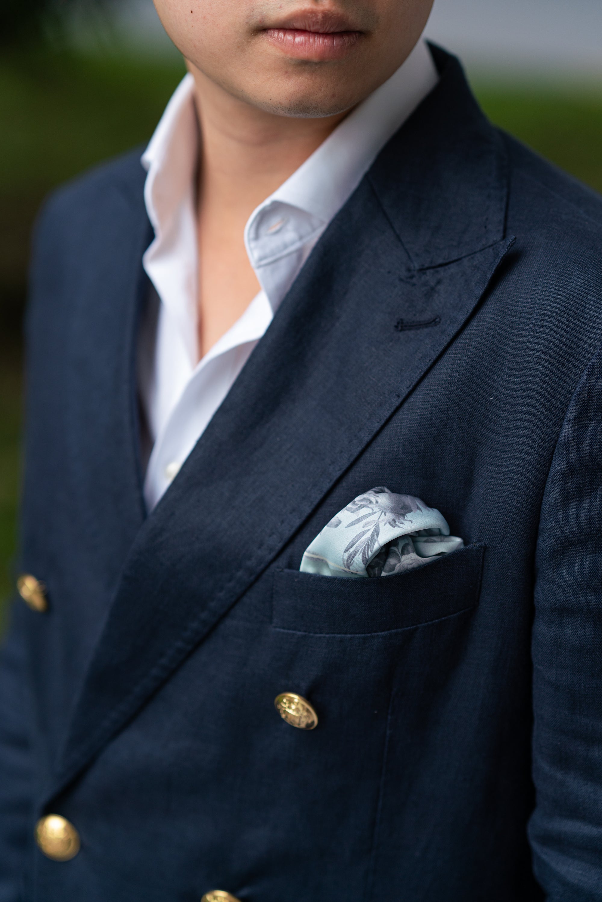 Man wearing a navy suit with a grey flower pocket square.