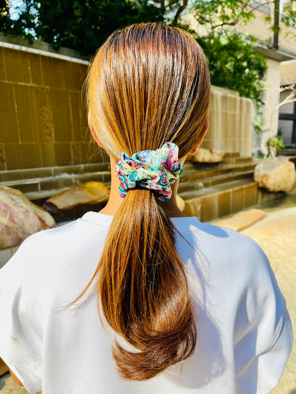 Woman wearing a multicoloured silk scrunchie with tiles and floral design