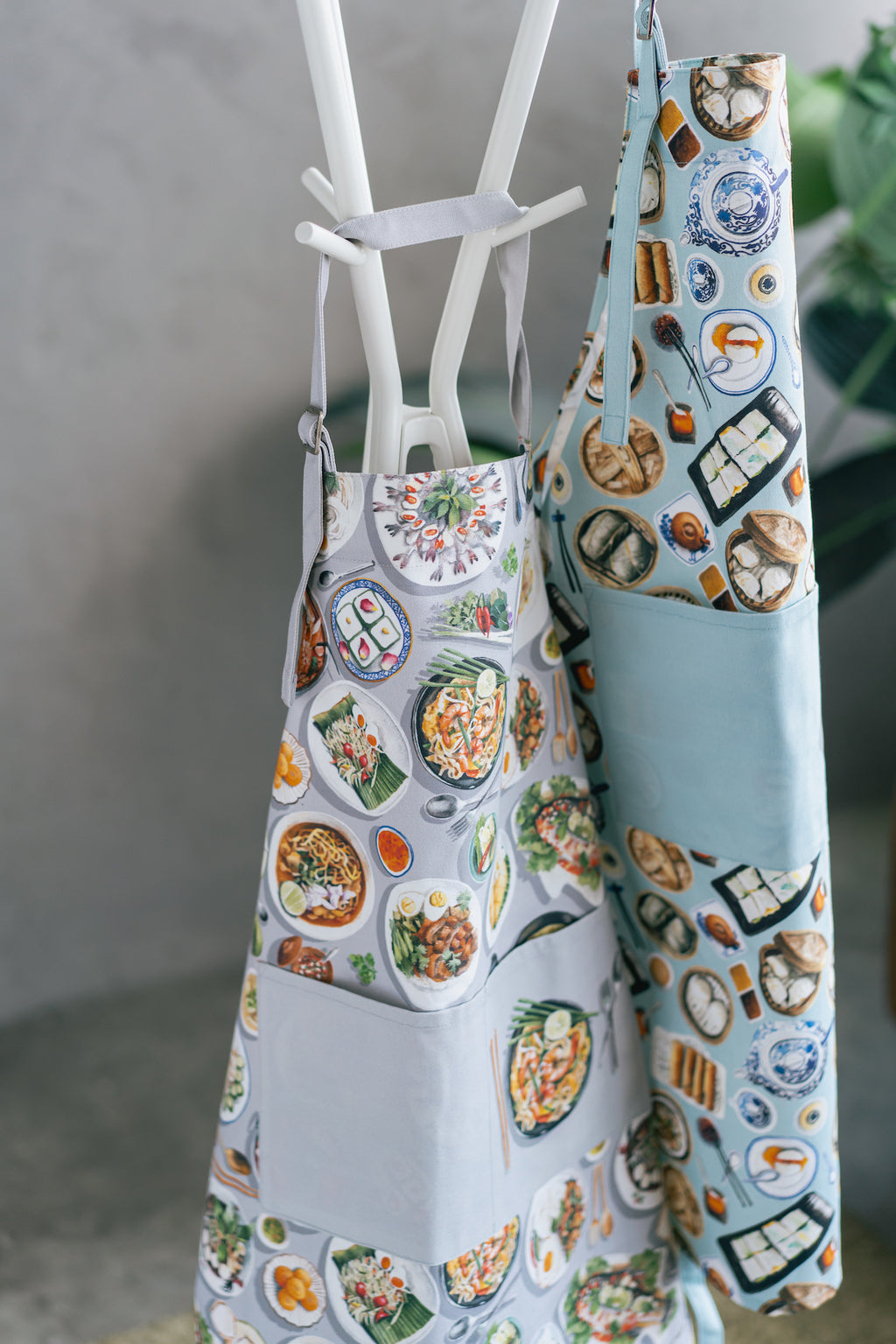 Apron with food design on a stand next to another apron