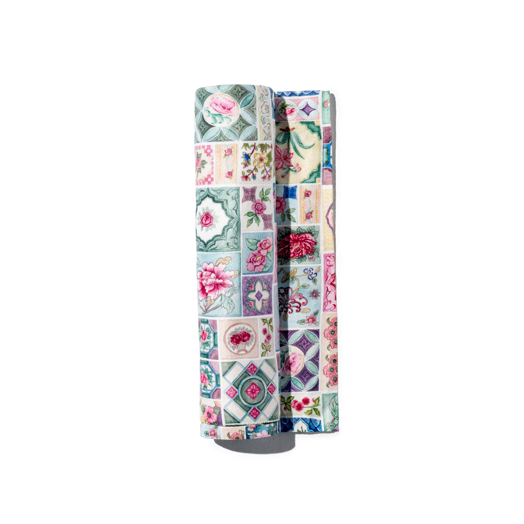 Singlapa baby towel with a multicolored floral tile pattern on a light background, folded loosely.