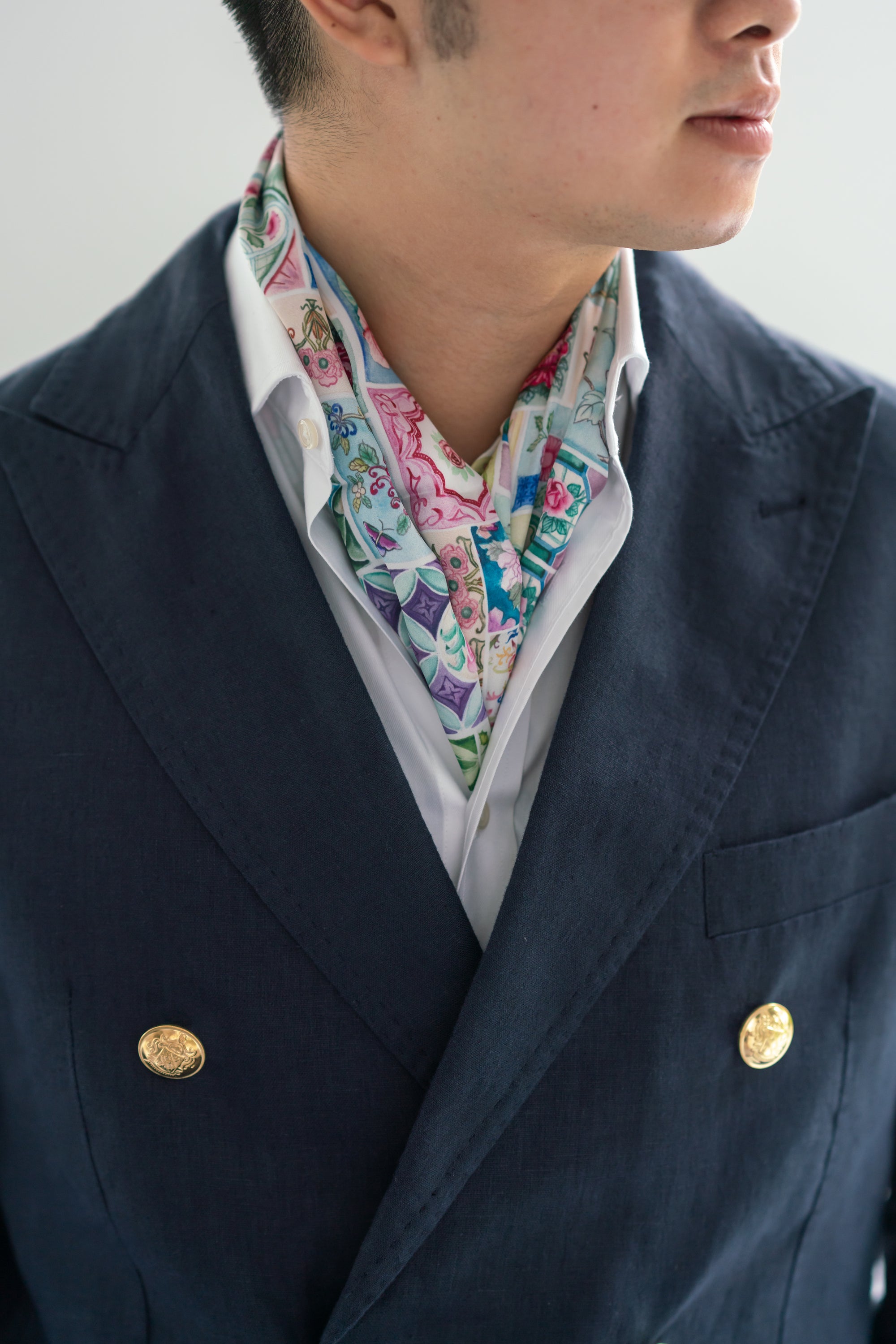 A person wearing a neck scarf with a multicolor floral pattern, paired with a dark jacket.