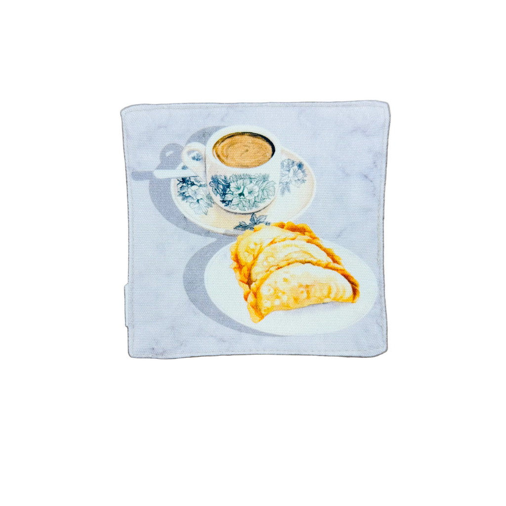 Kopi in an old school cup with a plate of curry puffs design on a fabric coaster.